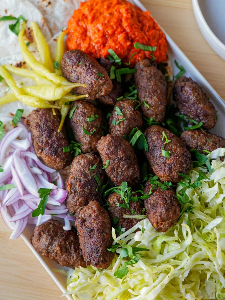 Juicy beef cevapi paired with sliced onions and pita